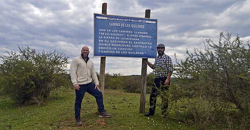 Richar Enry Ferreira y Nicolás Fariña junto al cartel indicador del Camino de los Quileros el día de la presentación del libro y del documental